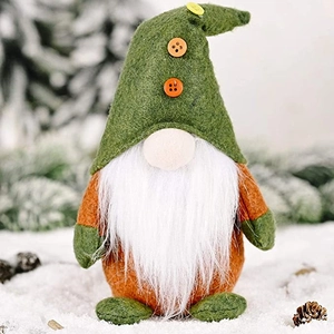 Christmas gnome plush decoration with green hat and orange buttons on outdoor snow background