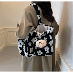 Detailed texture of black and white floral plush tote bag with a cute sheep charm pendant