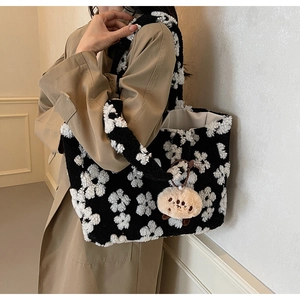Close-up of black plush tote bag with white flower patterns and a cute brown charm