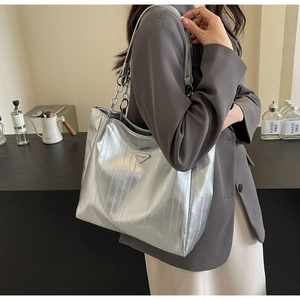Close-up of metallic silver tote bag with textured vertical stripes and chain strap