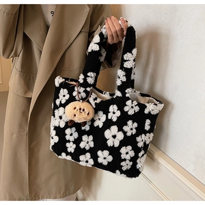 Detail of plush tote bag featuring black and white floral pattern with a cute bear charm