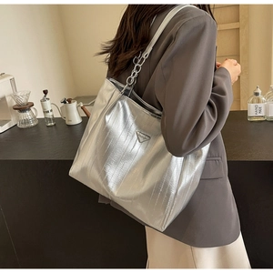Detailed view of large silver tote bag with metallic chain strap worn on shoulder