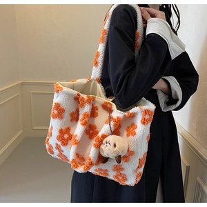 Detail of plush lamb wool tote bag with orange floral patterns and cute lamb pendant