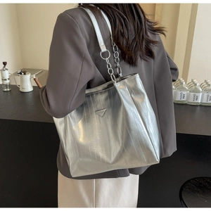 Detail showing silver metallic tote bag with chain strap and iconic triangle logo