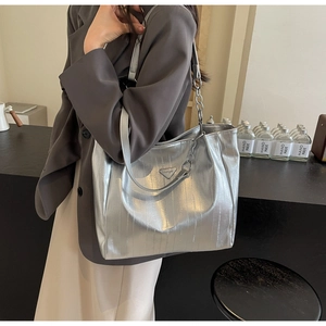 Detail of silver metallic tote bag with chain strap and triangle logo on textured material