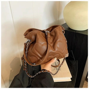 Close-up of brown heart-quilted shoulder bag with silver metal chain and corner guards