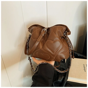 Close-up of quilted heart pattern and metal corners on a vintage brown shoulder bag