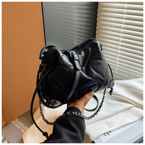 Close-up of heart-quilted shoulder bag with silver corner guards and chain strap detail