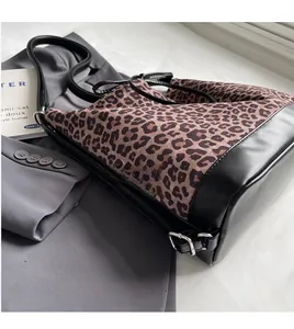 Detail of leopard print tote with adjustable black leather shoulder strap and metal buckle