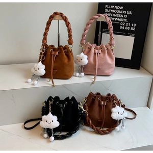 Four colorful suede bucket bags with braided handles and cloud charms on marble stand