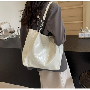 Detail of off-white patent leather tote bag with silver chain strap and metal logo