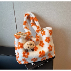 Detail of plush tote bag featuring orange floral patterns and a cute cartoon charm