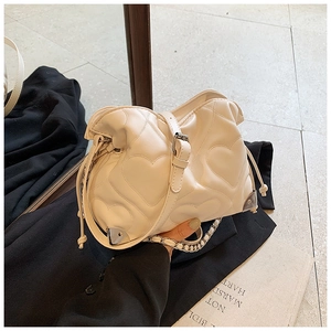 Detail of cream quilted shoulder bag with heart patterns and silver chain strap