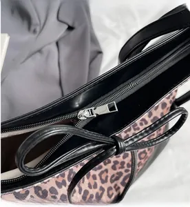 Detail of leopard print tote bag featuring smooth silver zipper and black leather trim