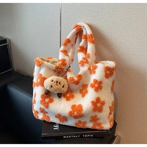 Detail of soft fleece tote bag featuring orange floral patterns and a cute plush charm