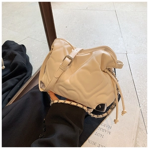 Detail of cream white heart-quilted shoulder bag with drawstring and tassel accents