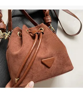 Detail of a brown suede bucket bag featuring a drawstring closure and a leather triangle logo