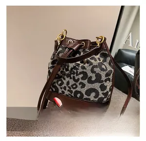 Detail of leopard print bucket bag featuring brown leather trim and drawstring closure