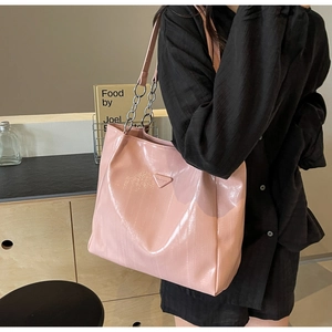 Detail of pink patent leather tote bag with glossy wrinkled texture and chain strap