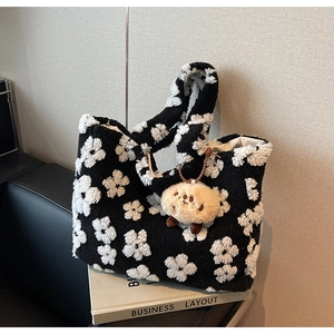 Detail of plush black tote bag with white floral pattern and cute lamb keychain pendant