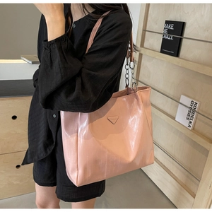 Pink glossy tote bag with vertical texture and silver metal chain strap shown on model