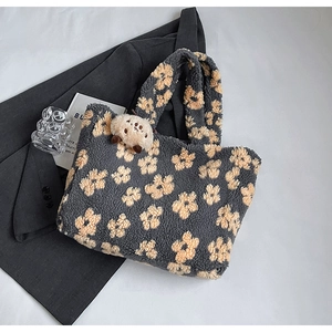 Detail of gray plush tote bag with yellow floral pattern and a bear keychain accessory