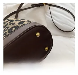 Detail of leopard print bucket bag featuring leather base and gold metal rivets