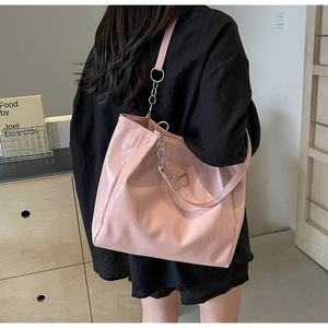 Close-up of pink glossy tote bag featuring metal chain strap and leather texture