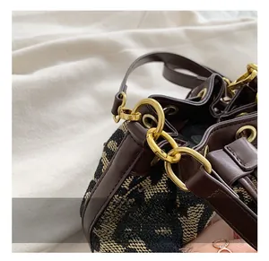 Detail of vintage bucket bag featuring brown leather trim and monogram jacquard fabric