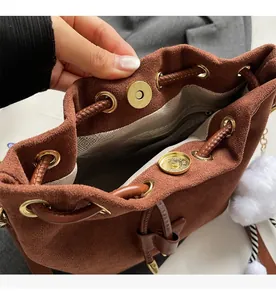 Close-up of brown suede bucket bag featuring gold magnetic hardware and drawstring