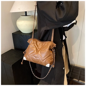 Detail of brown heart-quilted shoulder bag with silver metal corners and chain strap