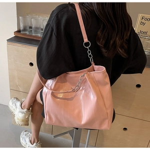 Pink embossed tote bag with silver chain strap shown in a modern lifestyle setting