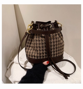 Detail of drawstring bucket bag with houndstooth fabric and brown leather trim