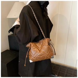 Detail of brown pleated heart-quilted leather bag with elegant chain strap and tassels