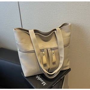 Dettaglio della borsa tote in tela beige con tre cerniere e ampie tracolle resistenti