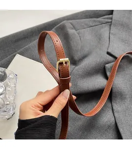 Detail of adjustable caramel leather shoulder strap with elegant gold metal buckle