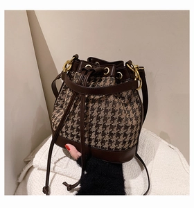 Detail of drawstring bucket bag with houndstooth fabric and brown leather trim