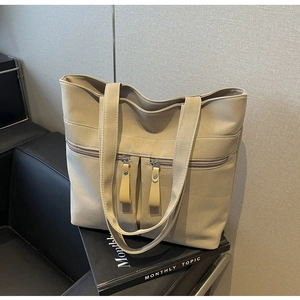 Dettaglio della borsa tote in tela beige con doppie tasche con zip e spallacci lunghi