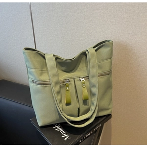 Dettaglio della borsa tote in tela verde erba con tre tasche anteriori con cerniera