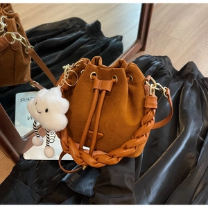 Detail of brown pleated bucket bag with braided handle and white plush cloud charm