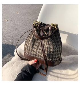 Close-up of contrast houndstooth bucket bag with leather trim and gold metal hardware