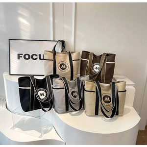 Presentación de bolsos tote grandes de lona en cinco colores con asas a rayas y bolsillos