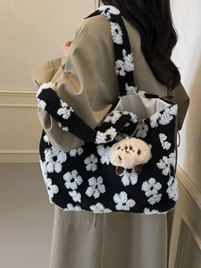 Plush floral tote bag with cartoon charm shown from a side view on a model