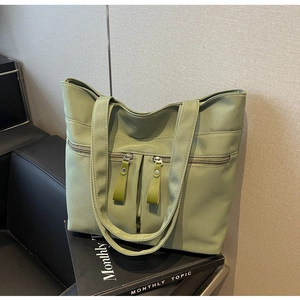 Dettaglio della borsa tote in tela verde chiaro con tasche multiple con zip sulla sedia