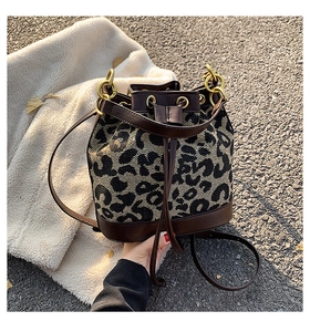 Detail of leopard print bucket bag with brown leather trim and golden metal rings