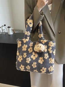 Fuzzy floral tote bag in grey-blue with bear charm carried by model in a cozy cafe