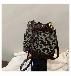 Close-up of leopard pattern woven fabric and brown leather trim on retro bucket bag