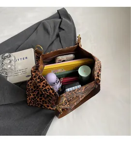 Top view of spacious leopard print bag interior holding umbrella, phone, and wallet