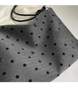 Détail du sac cabas en tissu à chevrons avec pois noirs et broderie de papillons