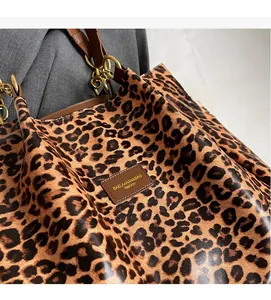 Close-up of leopard print pattern with leather handle and golden metal ring hardware